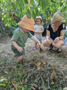 Eine junge Frau mit zwei kleinen Kindern hocken im Gras