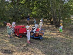 Kinder mit Erzeiherin im Wald unterwegs.